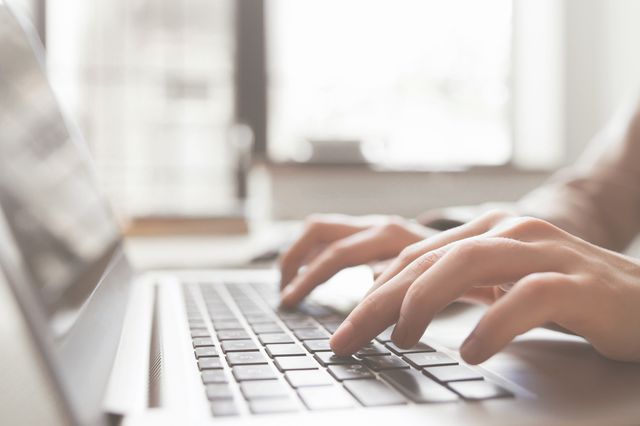 A stock photo showing fingers typing on a laptop.